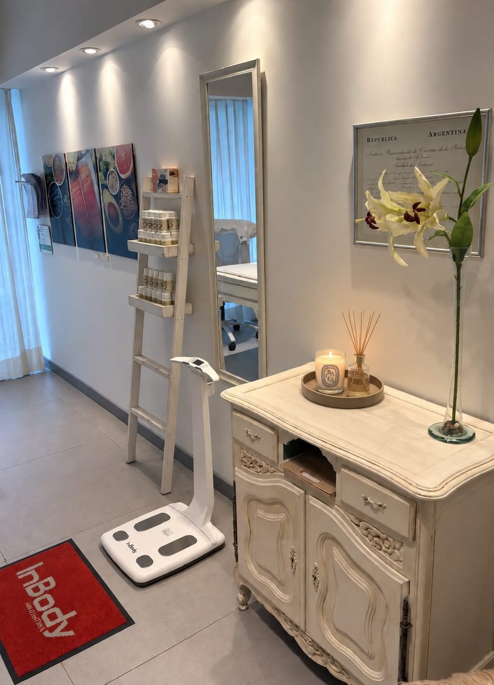 Consultorio de Alma Nutrición: balanza de composición corporal, espejo, cómoda blanca con velas y flores
